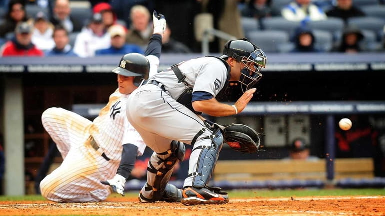 The Yankees' Russell Martin slides past Tigers catcher Alex Avila...