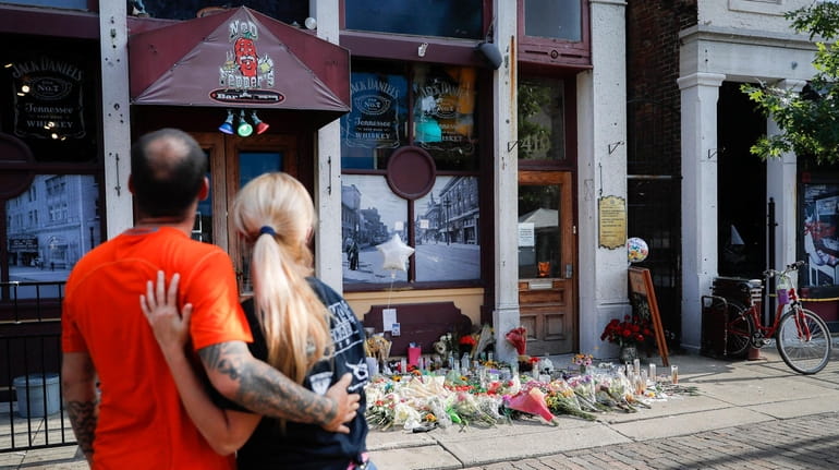 Mourners pause at a makeshift memorial outside Ned Peppers bar...