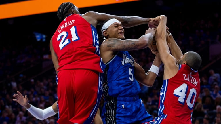 Orlando Magic's Paolo Banchero, center, gets fouled by Philadelphia 76ers'...