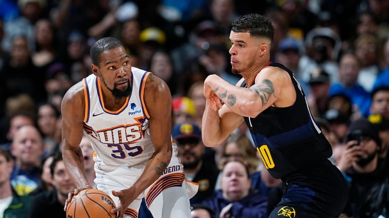 Phoenix Suns forward Kevin Durant, left, is defended by Denver...