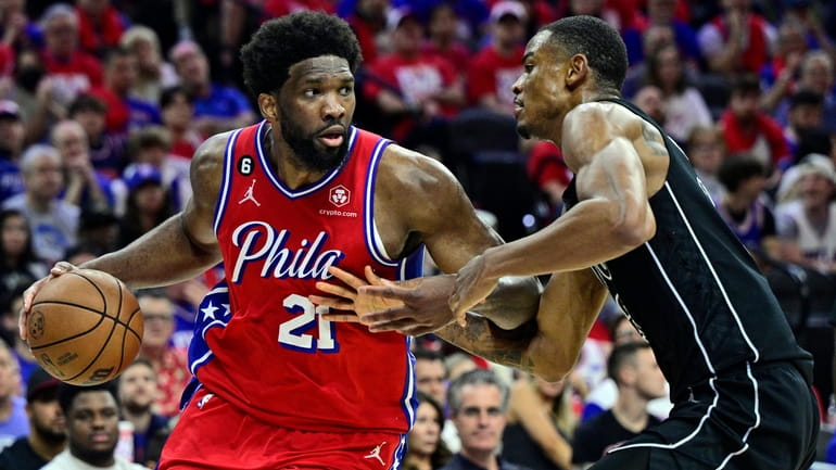 The 76ers' Joel Embiid, left, dibbles the ball as the...