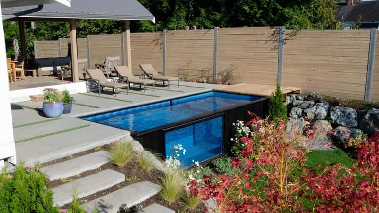 A shipping container pool is surrounded by decking on three...