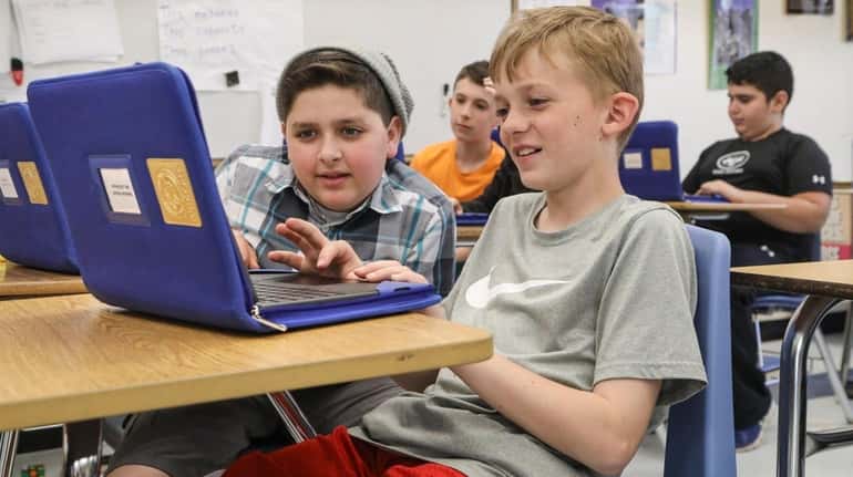Sixth-graders Torre Cintorino, left, and Liam McGuire work with their...