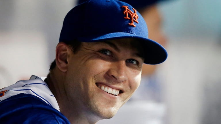 Mets pitcher Jacob deGrom smiles in the dugout after the...