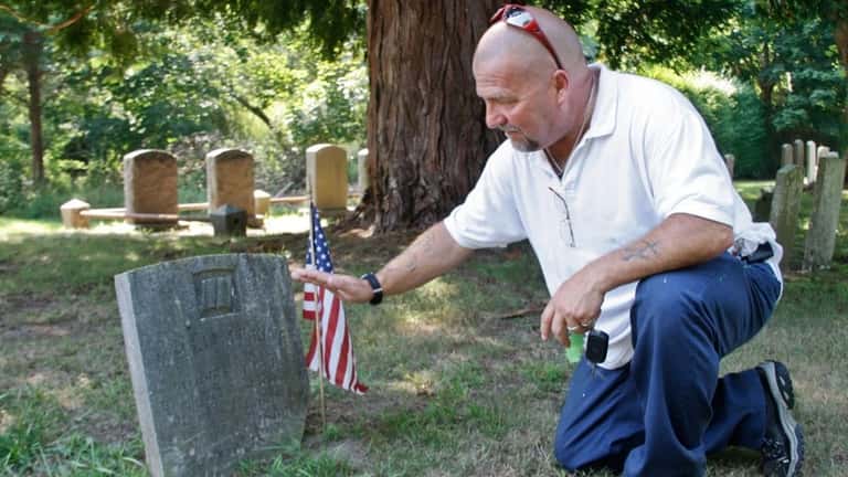 Keith Jackowski of Farmingdale touches the gravestone of his ancestor,...