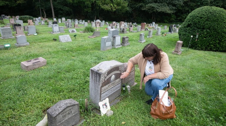 Linda Ortado, of Massapequa Park, visits the graves of her...