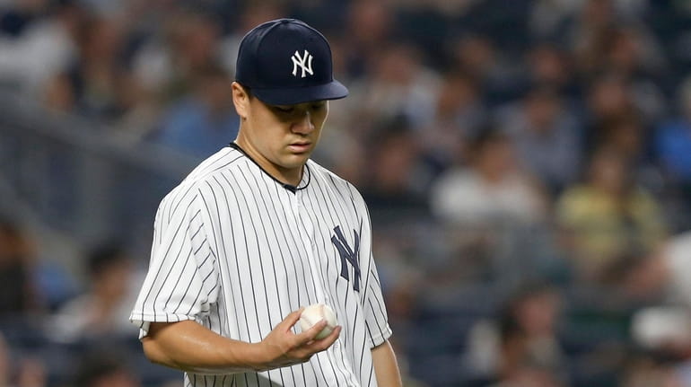 Masahiro Tanaka of the Yankees looks at the ball after...