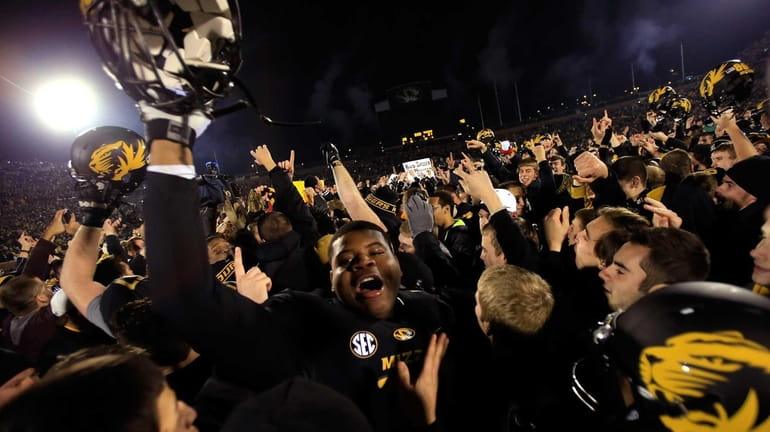 Missouri Tigers players celebrate as fans rush the field after...