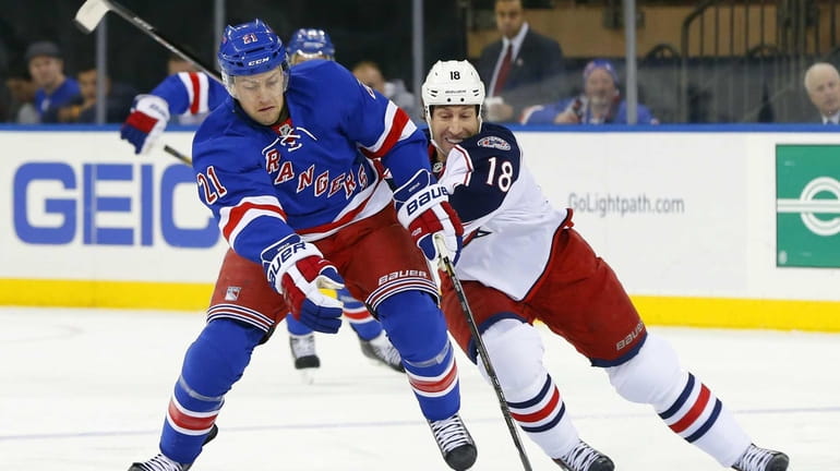 Derek Stepan tries to carry the puck up ice against...