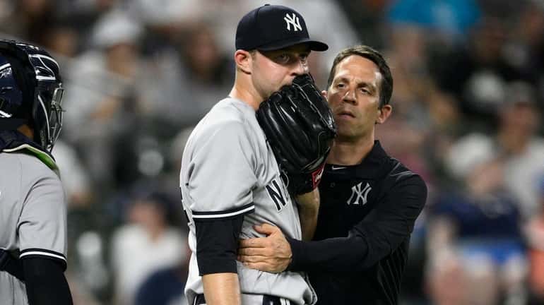 Yankees relief pitcher Michael King, center, is tended to by...