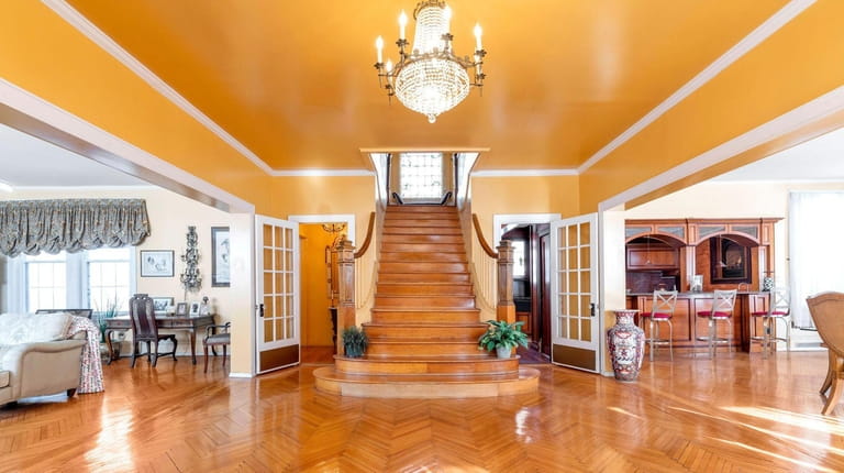 A grand staircase in the foyer leads to a Tiffany-style stained...