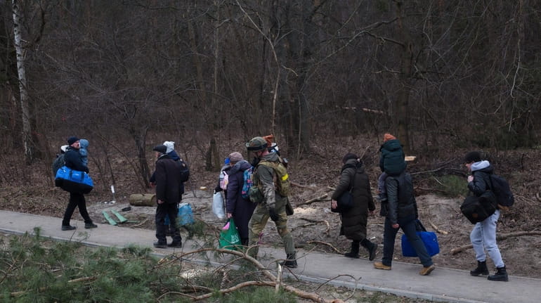 People evacuate from Irpin, Ukraine on Sunday with the help...