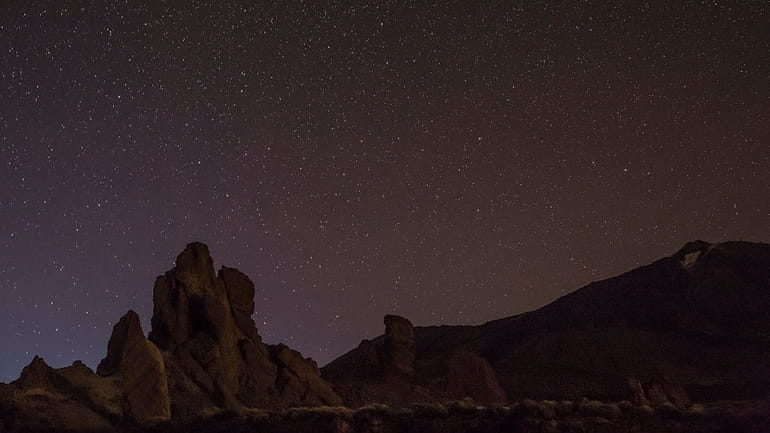 Stars illuminate the sky above a rock formation in the...