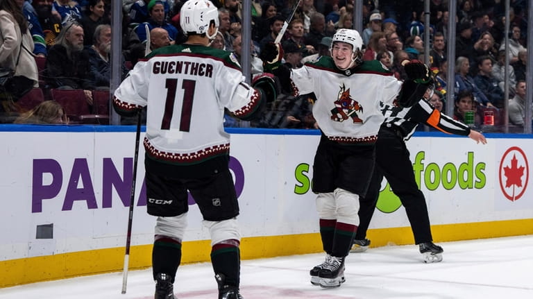 Arizona Coyotes' Dylan Guenther (11) celebrates with Logan Cooley (92)...