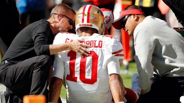 Trainers attend to 49ers quarterback Jimmy Garoppolo who was injured after...