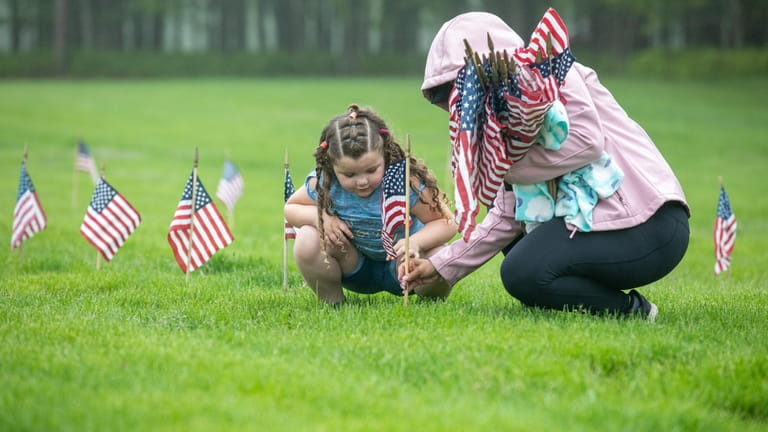 Skylar Strouse, 4, of Coram, helps place a flag at Calverton National...