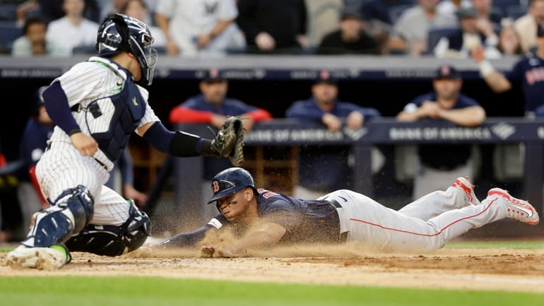 Rafael Devers #11 of the Boston Red Sox dives home...