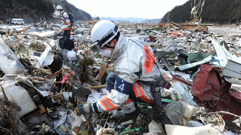 Rescue workers search through debris in Minamisanriku, Miyagi prefecture. (March...