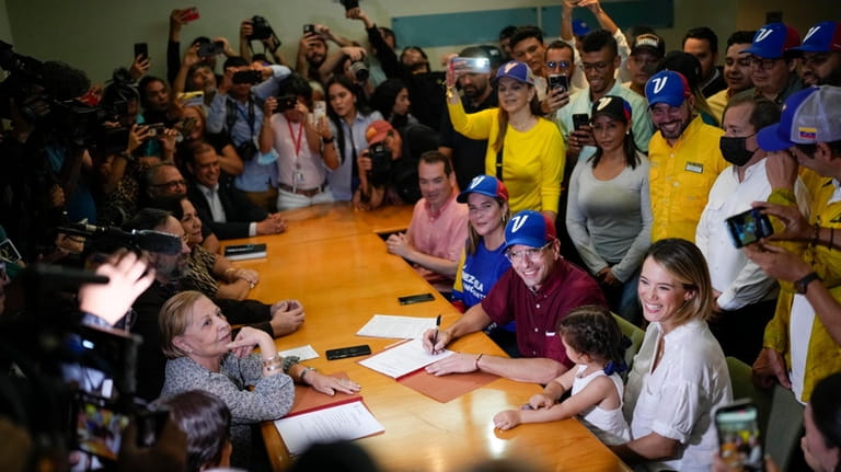 Opposition leader Henrique Capriles, center right, sitting, smiles after registering...
