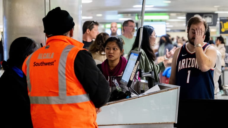Travelers wait in line for assistance with lost luggage at...