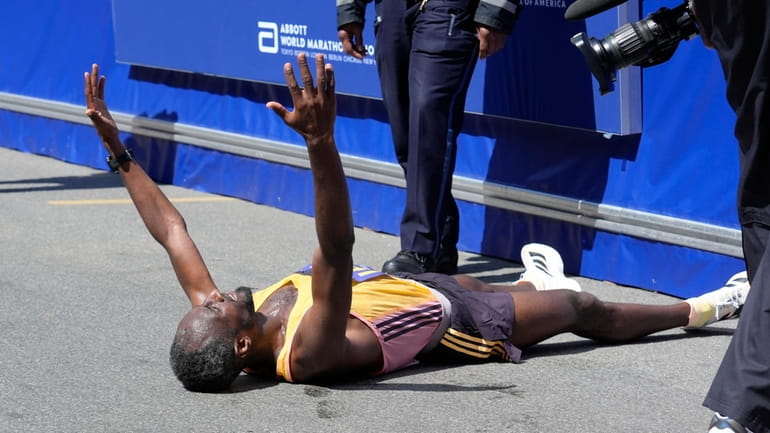 Sisay Lemma, of Ethiopia, celebrates while lying down after winning...
