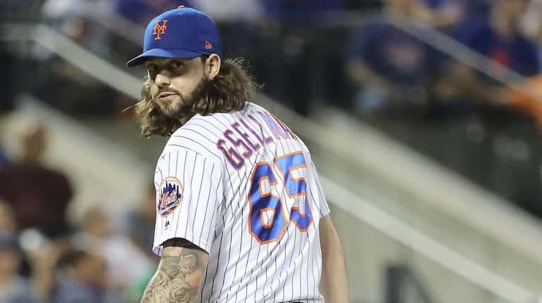 Mets relief pitcher Robert Gsellman checks the runner at first during the...