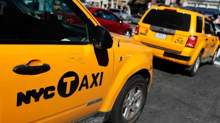 Two gas-electric hybrid taxi cabs drive on a street, March...