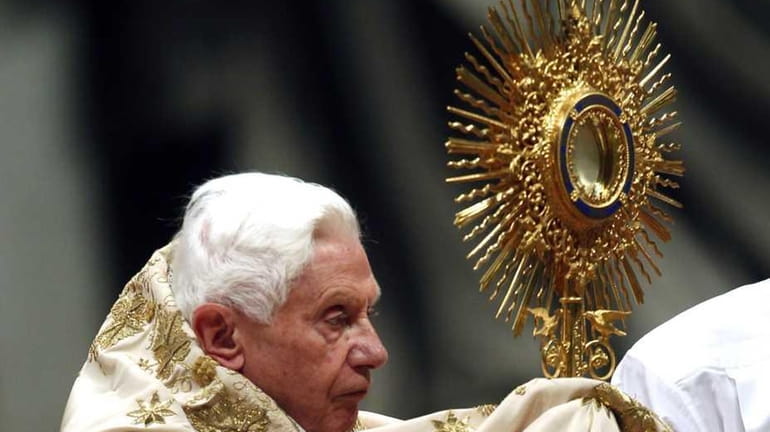 Pope Benedict XVI holds the ostensory as he celebrates a...