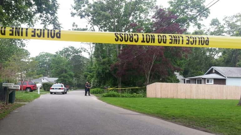 Suffolk County police investigate the scene near a home, at...