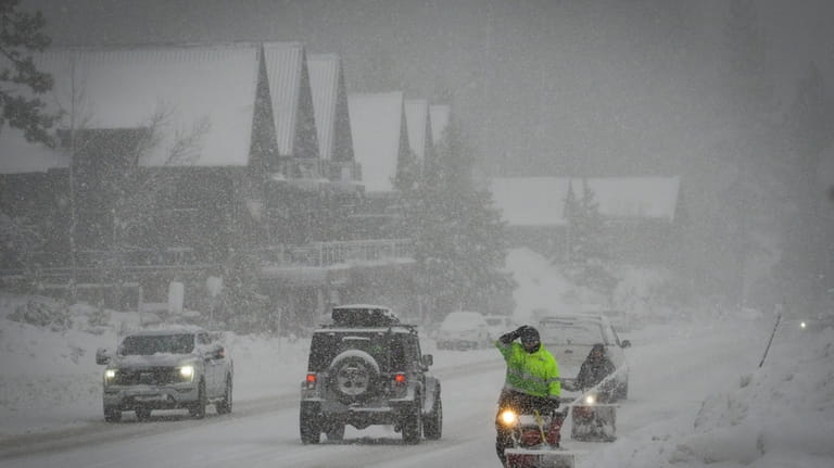 Workers attempt to clear a road with snow blowers during...