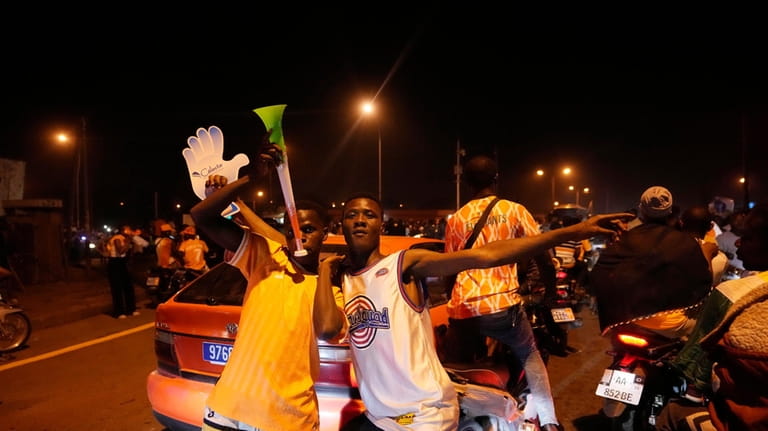 Ivory Coast soccer fans celebrate on a street in Bouake,...