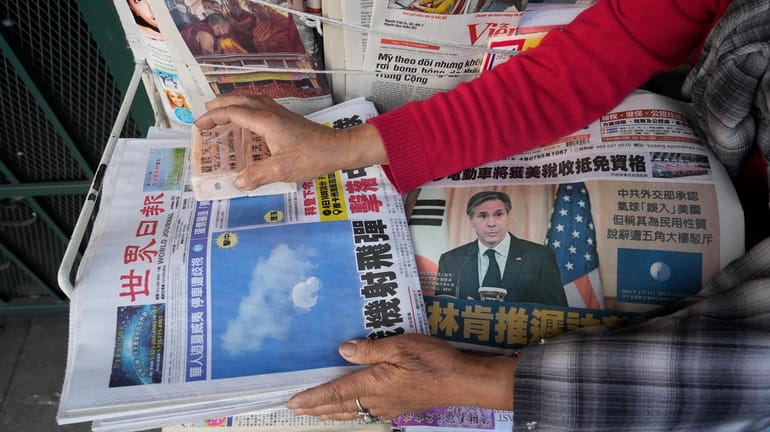 Business owner "Annie" weights down copies of the Chinese Daily...