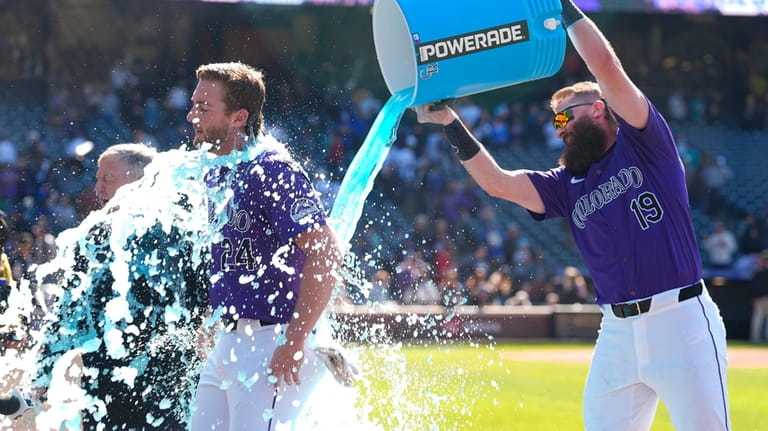 Colorado Rockies' Ryan McMahon, left, is doused by teammate Charlie...