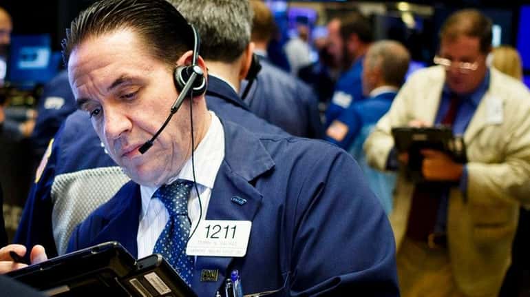 Traders work on the floor at the opening bell of...
