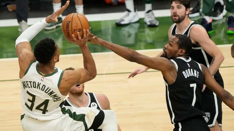 The Bucks' Giannis Antetokounmpo shoots over the Nets' Kevin Durant...