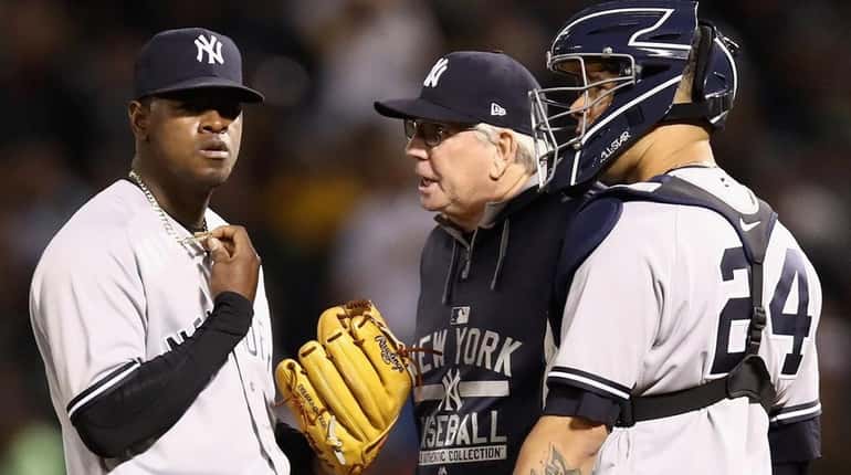 Luis Severino talks to pitching coach Larry Rothschild and catcher...