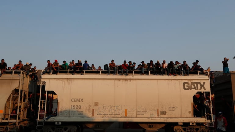 Central American migrants ride atop a freight train during their...