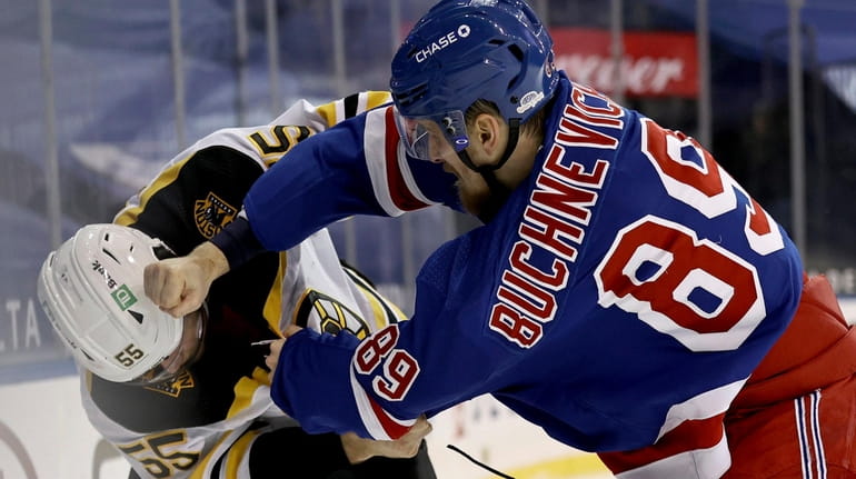 The Bruins' Jeremy Lauzon and the Rangers' Pavel Buchnevich fight in the...