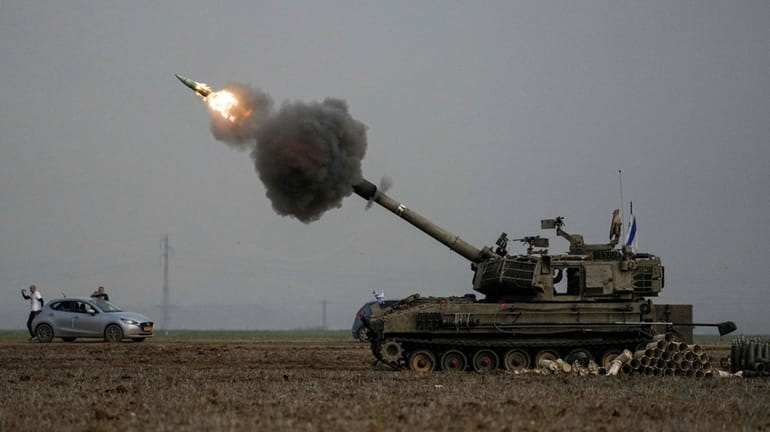 An Israeli mobile artillery unit fires a shell from southern...
