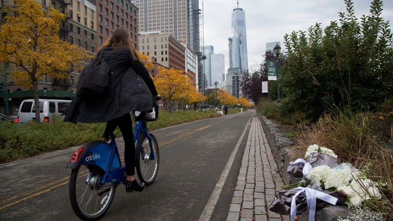 A bicyclist passes bouquets of flowers left by Argentine President...