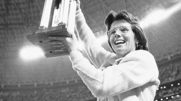 Billie Jean King holds the winner's trophy high in the...