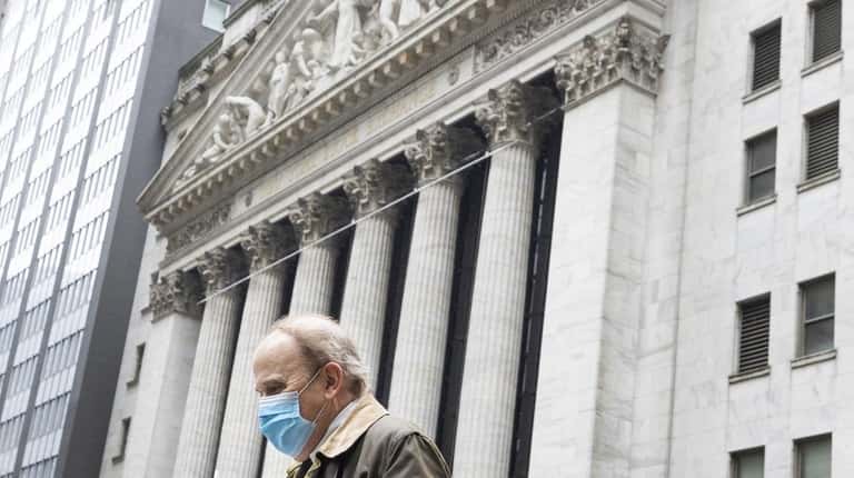 A man wearing a protective mask walks Monday past the New...
