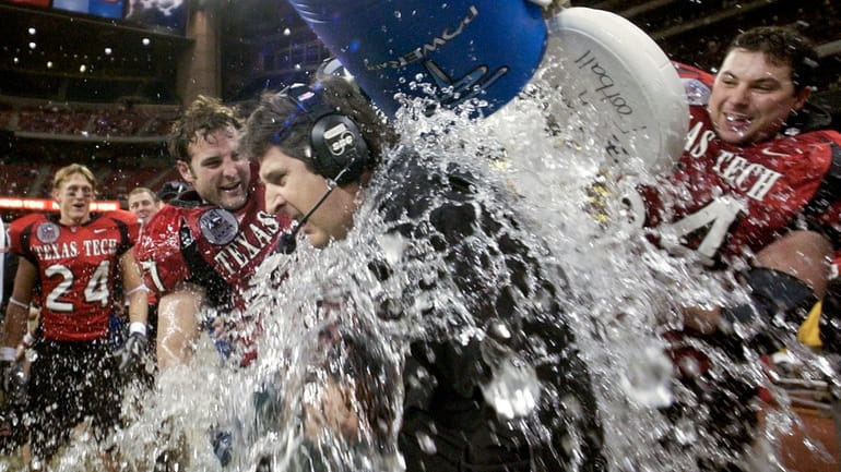 Texas Tech coach Mike Leach, center, is dunked with water...