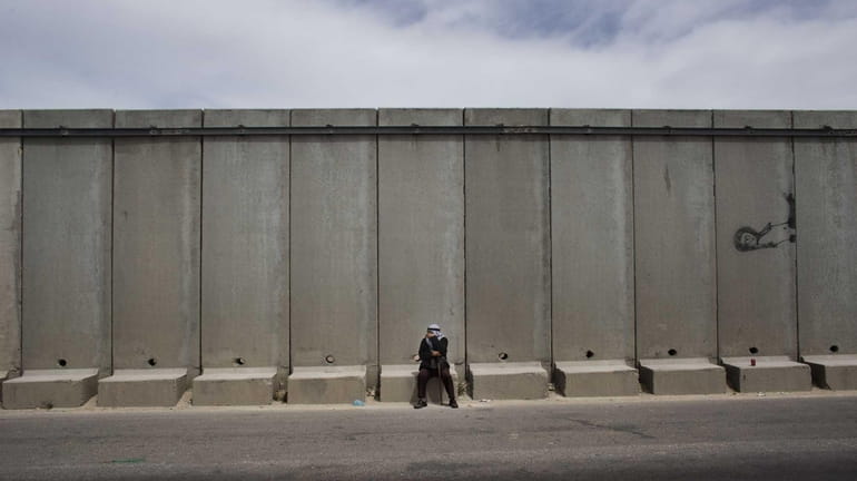 A Palestinian man pauses near the Qalandia checkpoint between the...
