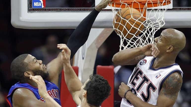 Detroit Pistons' Greg Monroe, left, dunks over New Jersey Nets'...