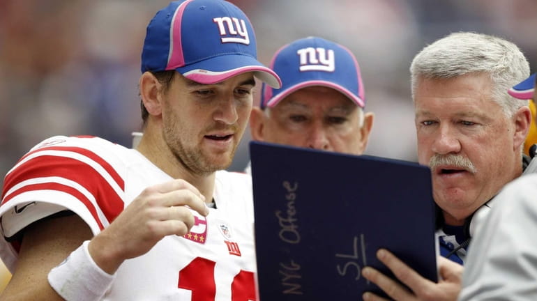 Quarterback Eli Manning of the Giants looks over plays with...