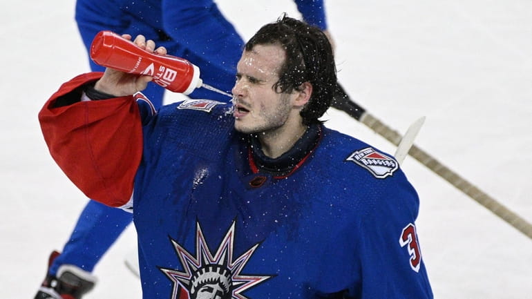 Rangers goaltender Igor Shesterkin sprays his face with water during...