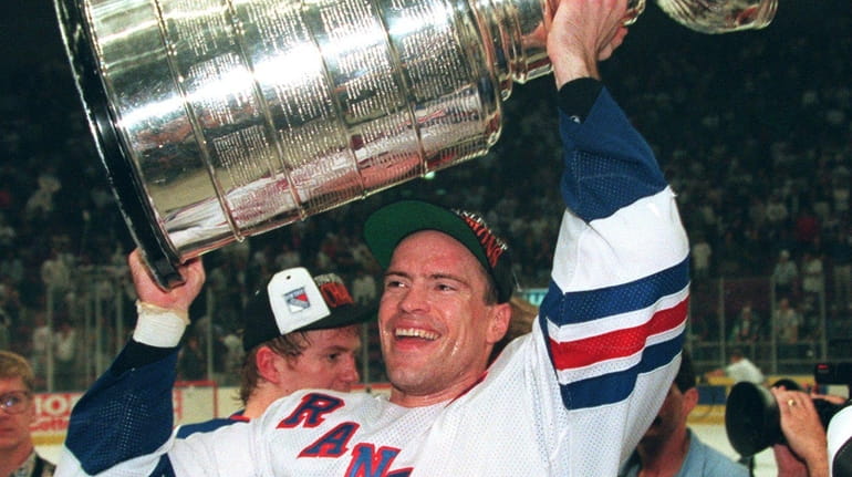 Rangers captain Mark Messier hoists the Stanley Cup over his...