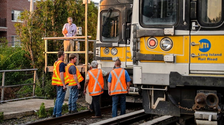 MTA employees inspect an LIRR train that struck a car...