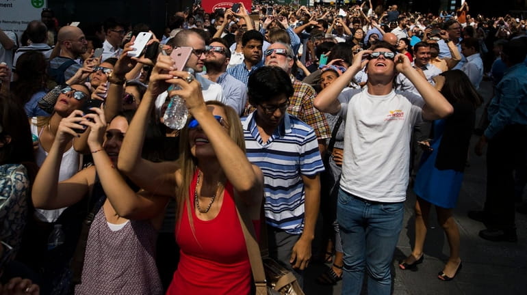 A crowd reacts to the view of a partial solar...